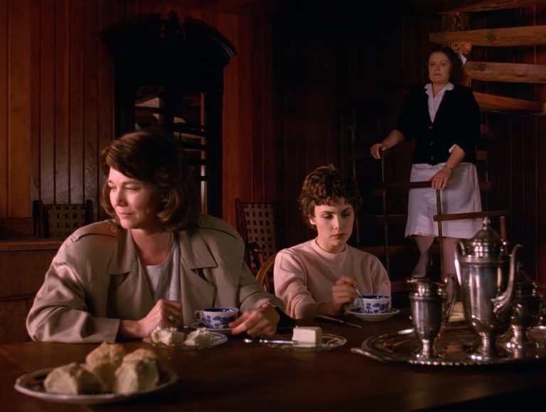 Sylvia and Audrey Horne at a dining room table with a Nurse on a staircase