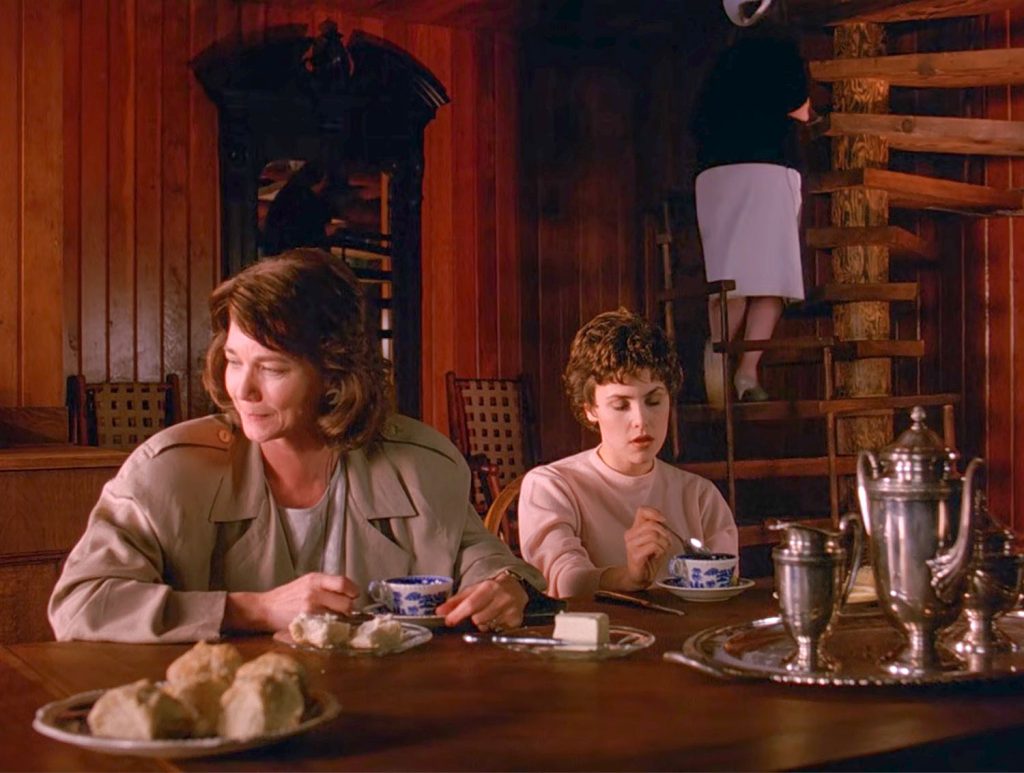 Sylvia and Audrey Horne at a dining room table with a Nurse on a staircase
