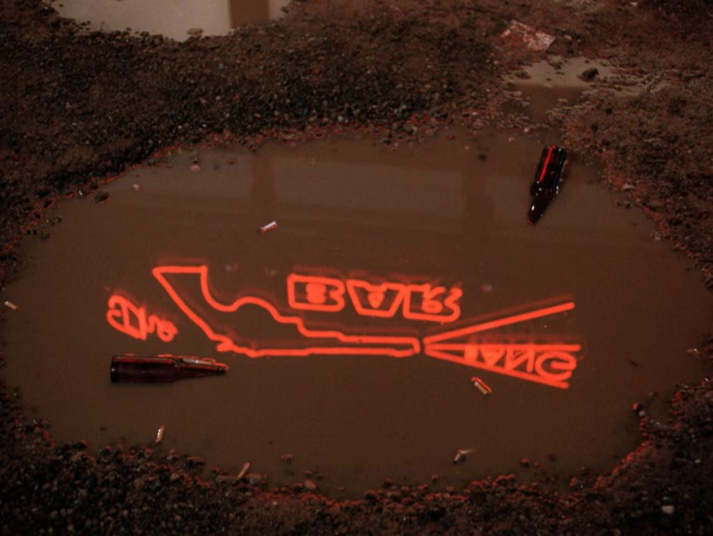 Reflection of neon "Bang Bang Bar" sign in a puddle