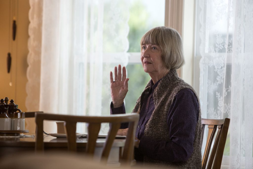 Betty Briggs sitting at a table holding her hand up
