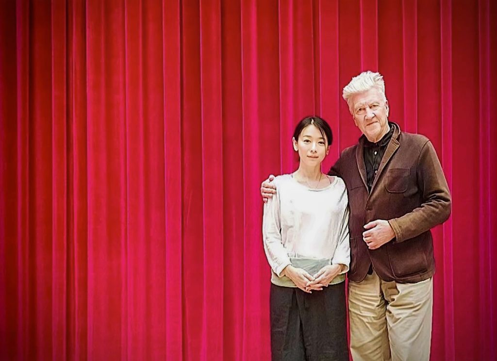 Nae Yuuki and David Lynch in front of a red curtain