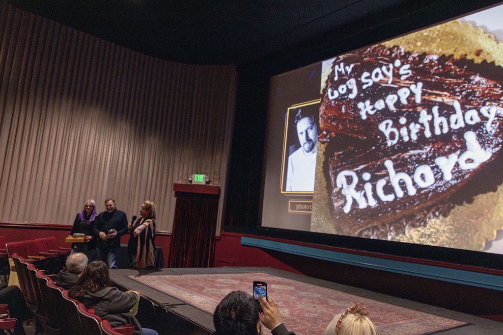 Movie screen in a theatre with people talking