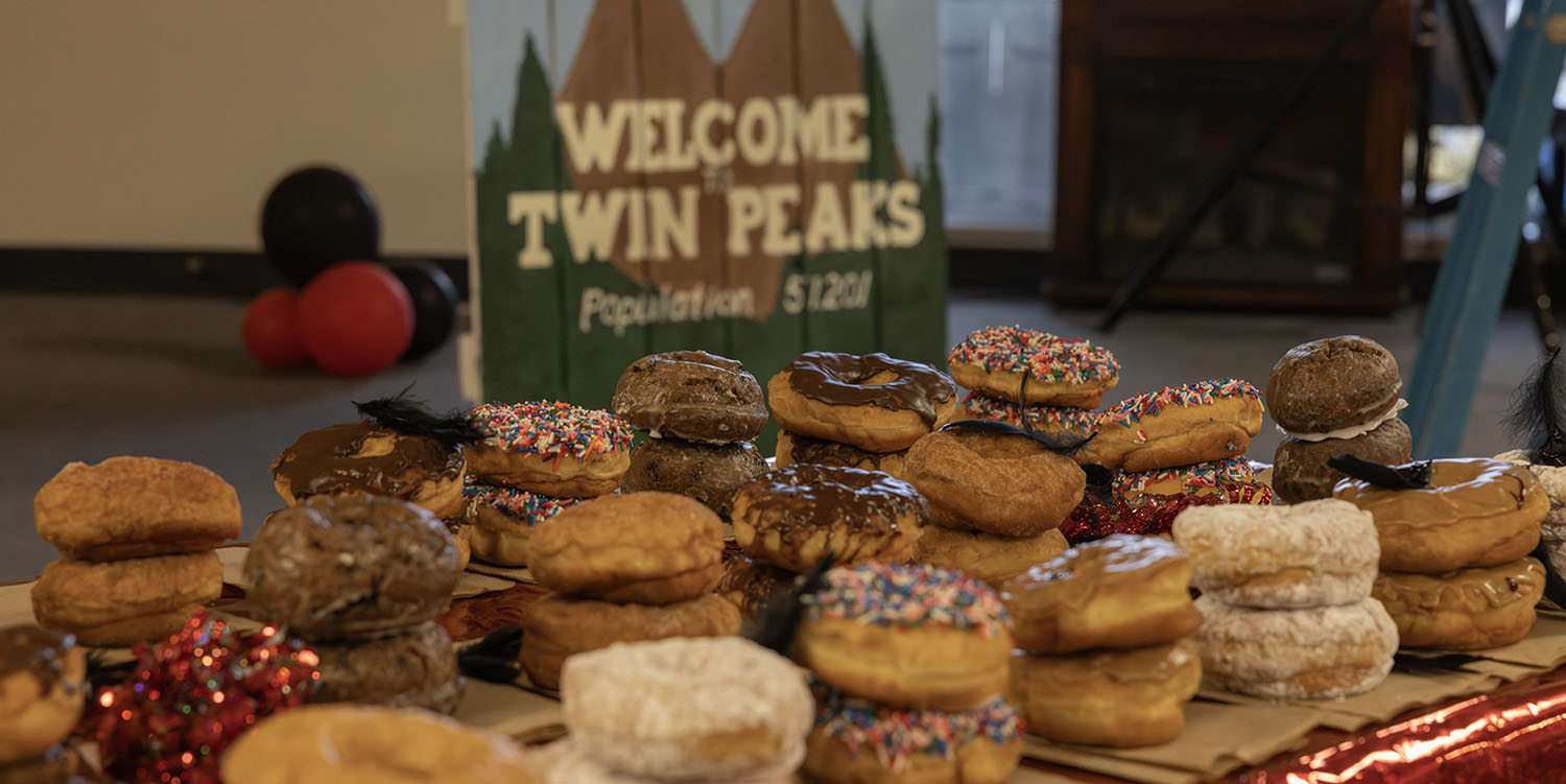 Stacks of doughnuts with "Welcome to Twin Peaks SIgn" in distance