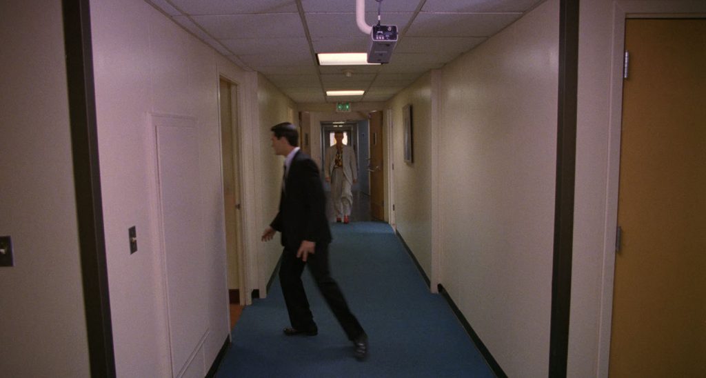 Special Agent Dale Cooper in the hall with Jeffries in the distance