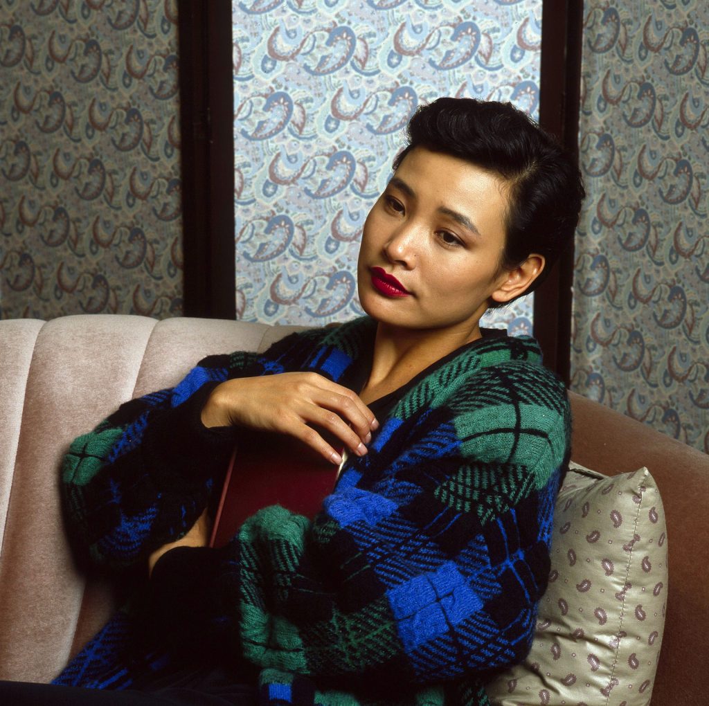 Joan Chen as Josie Packard sitting on a couch holding a book