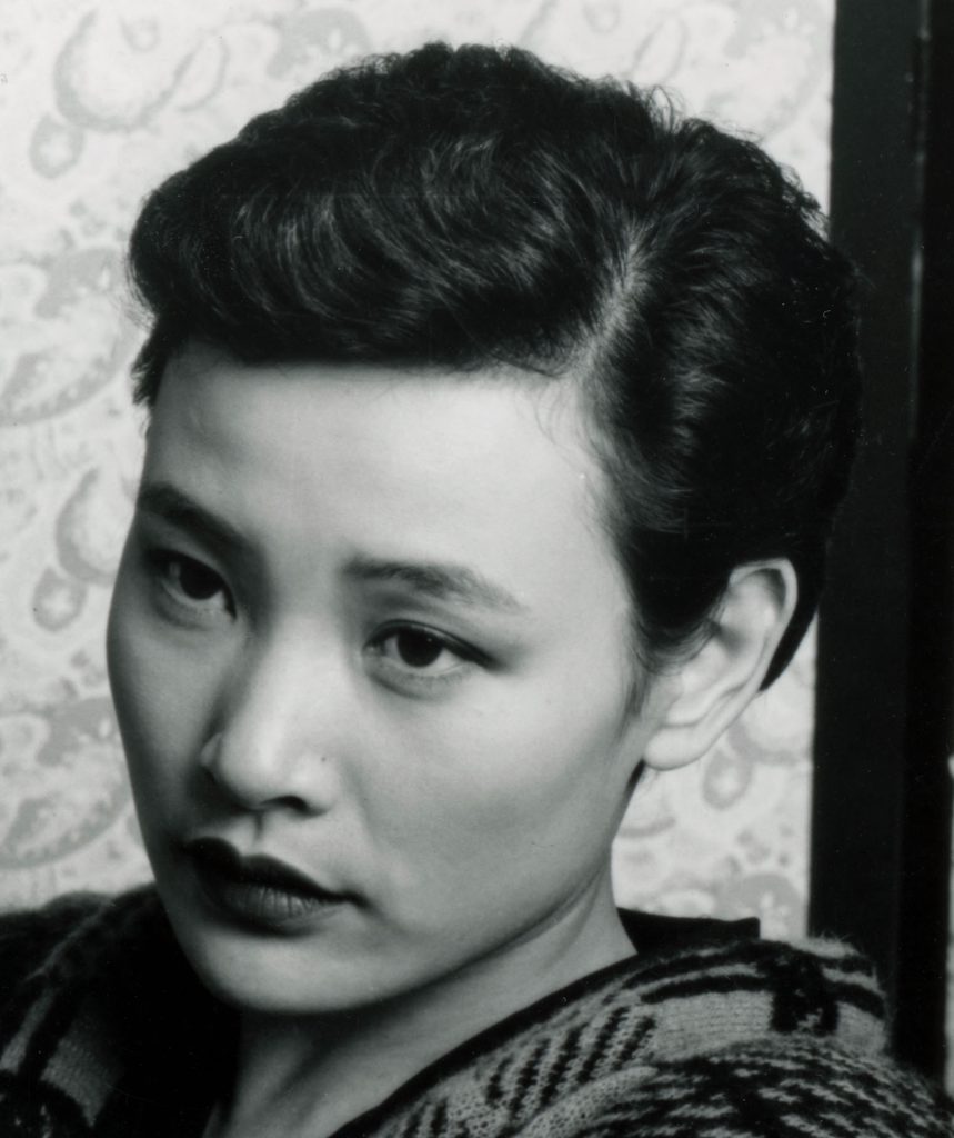 Cropped image of Joan Chen as Josie Packard sitting on a couch holding a book