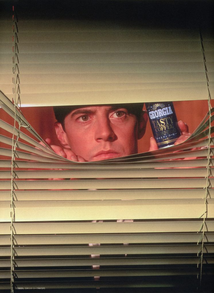 Dale Cooper looking through blinds holding a can of Georgia Coffee