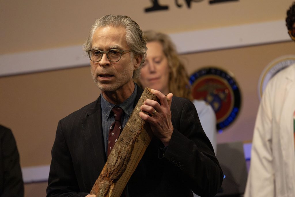 Improv actor holding a log on stage