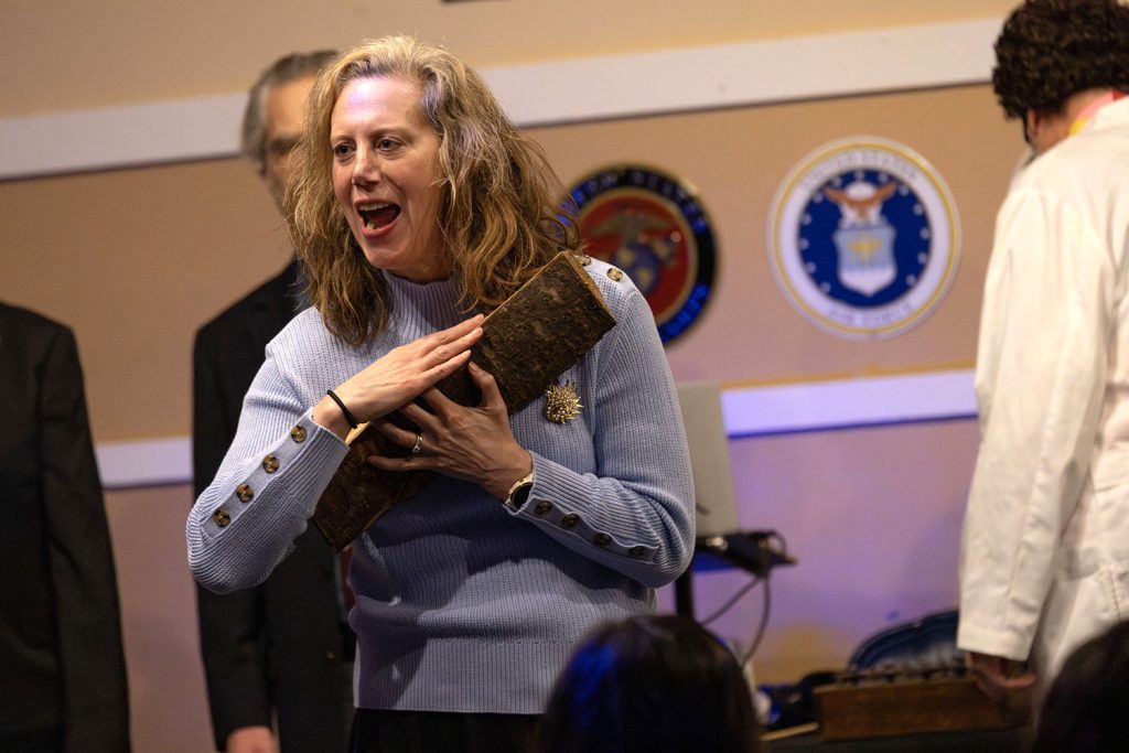 Improv actor holding a log on stage