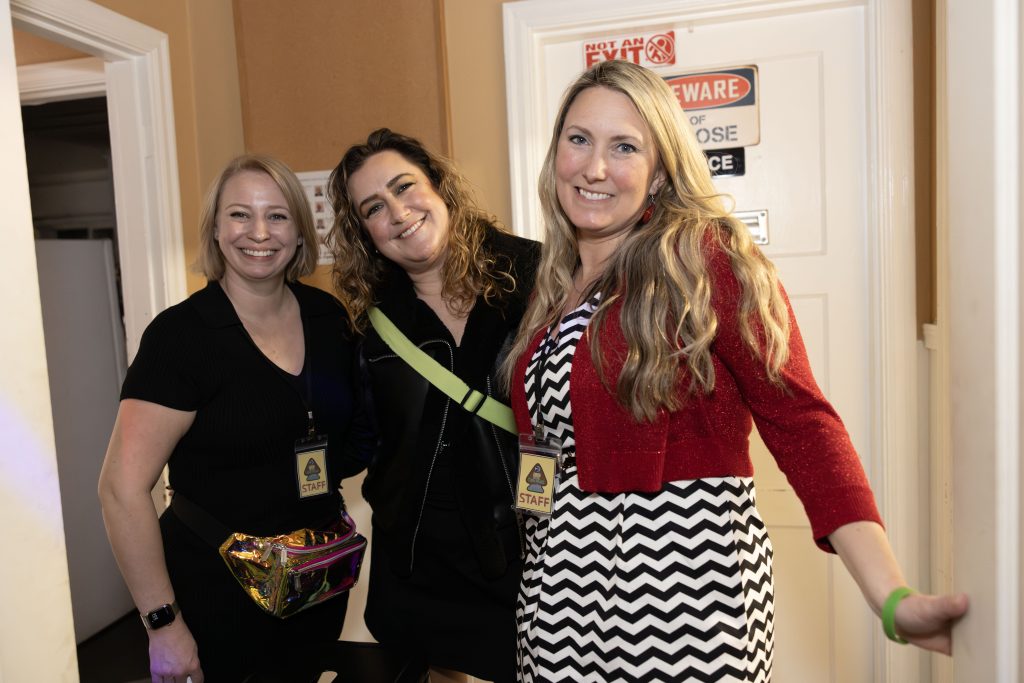 Three people standing in a bar