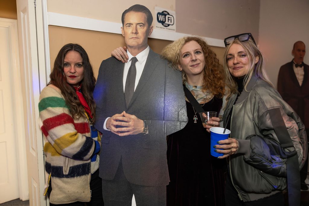 Three people standing next to a standee of Special Agent Dale Cooper
