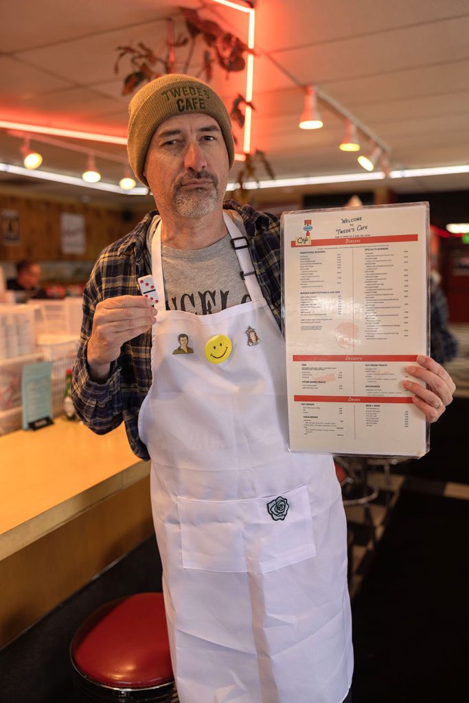 Scott Ryan dressed as Hank Jennings holding a Twede's Cafe menu
