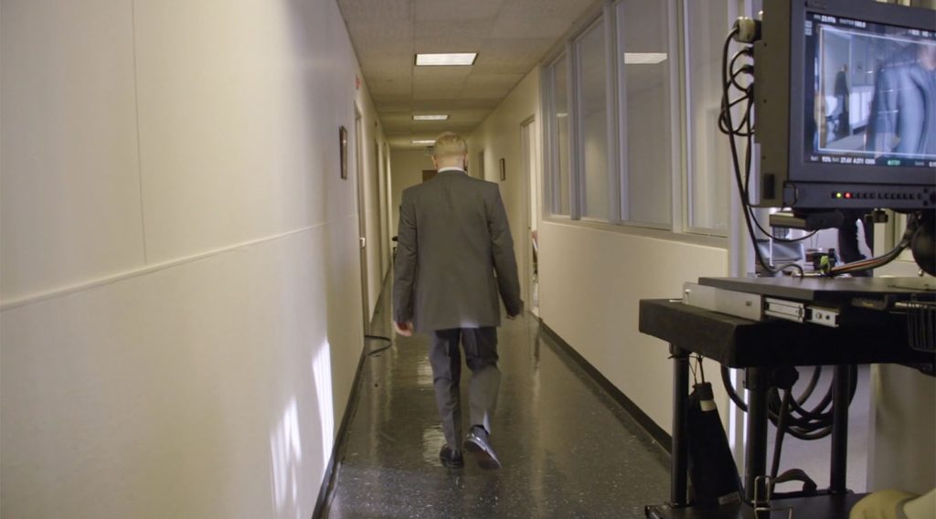 Behind the scenes photo of Owain Rhys Davies walking down the hall