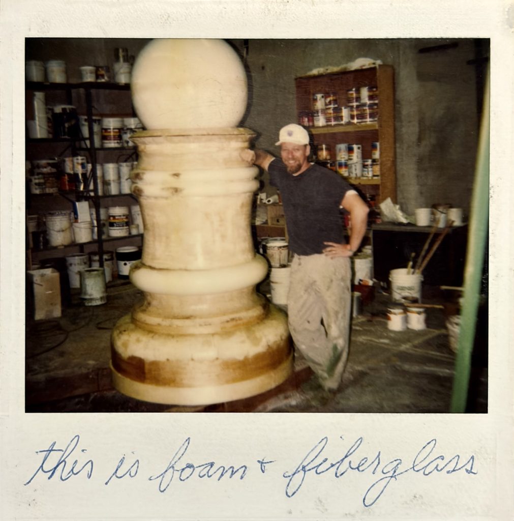 Polaroid photo of Dave Robinson standing next to giant pawn
