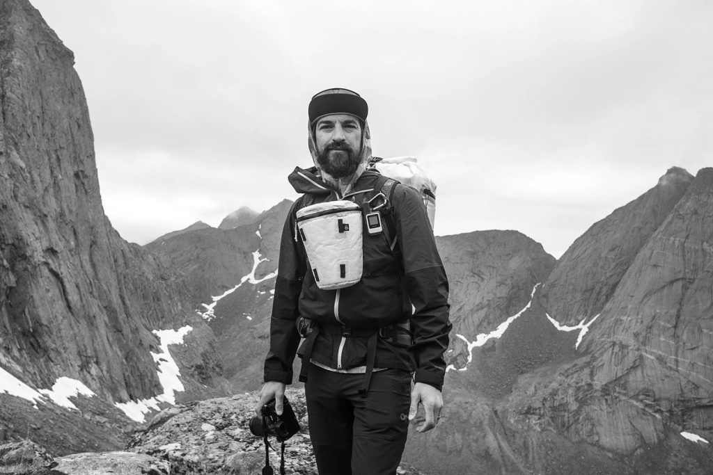 Scott Rinckenberger holding a camera while standing between two mountains