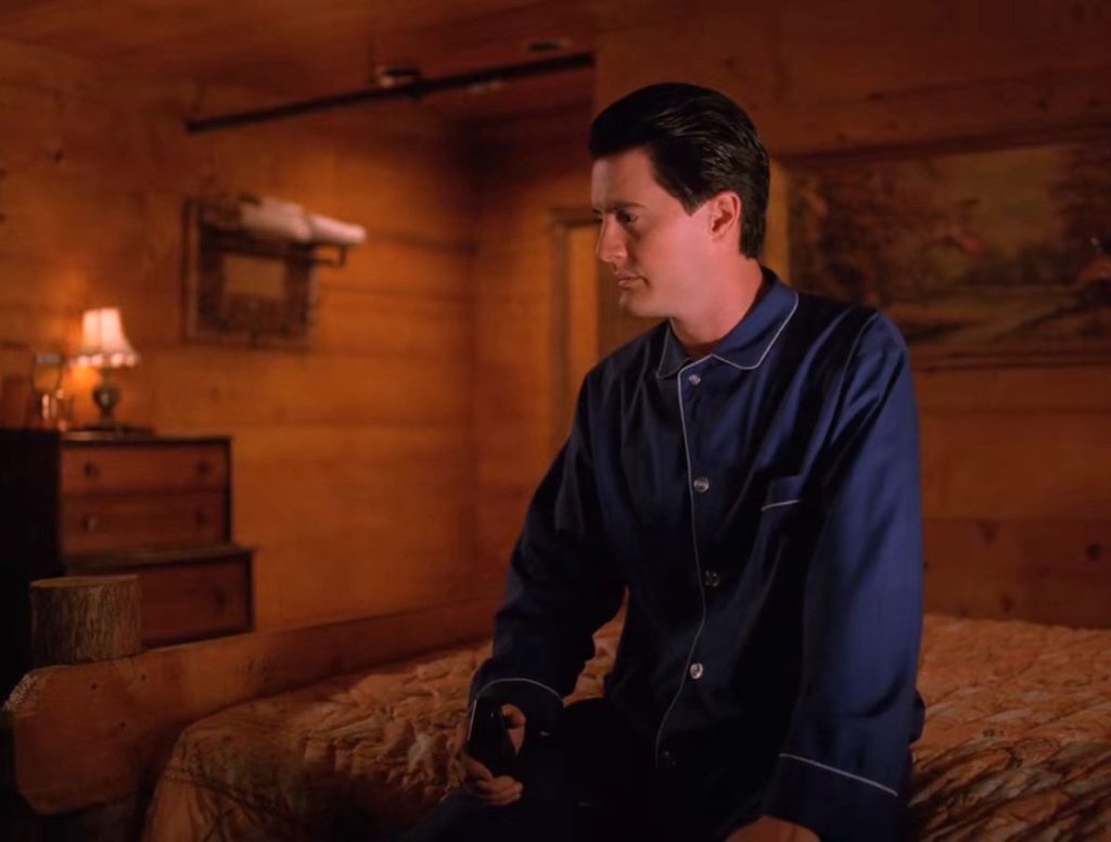 Agent Dale Cooper sitting on his bed in room 315