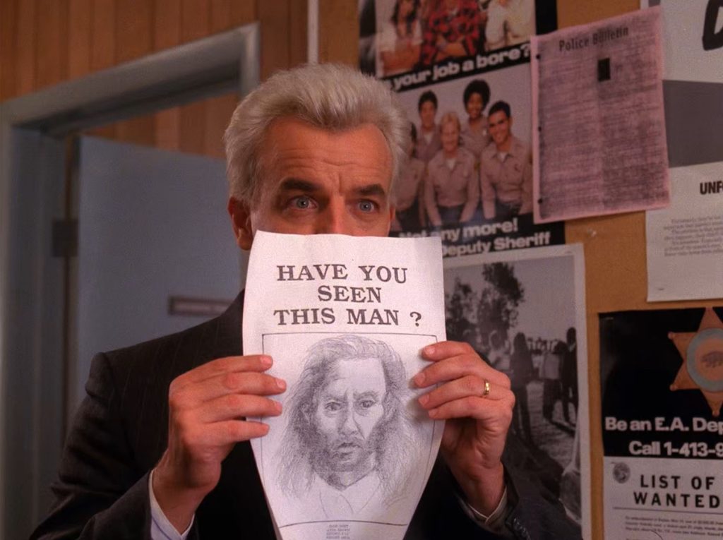 Leland Palmer holding up a "Have you Seen this Man" poster
