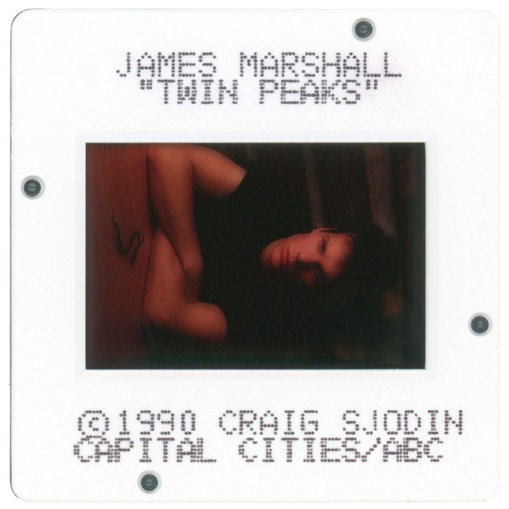 Photo slide of James Marshall as James Hurley sitting at a table with the other half of Laura Palmer's half-heart necklace