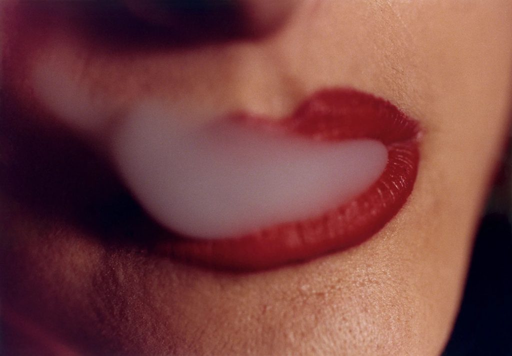 Mouth with red lips blowing smoke