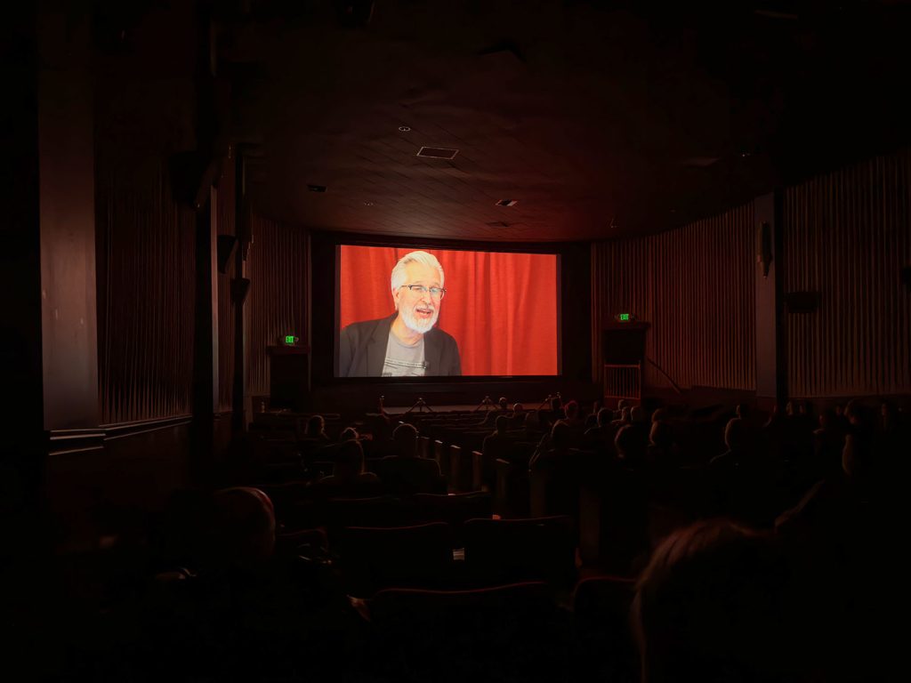 Steven Miller speaking on the North Bend Theatre screen