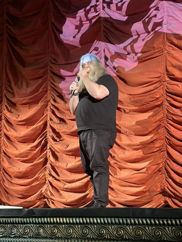 Daniel Knox eating a sandwich on stage