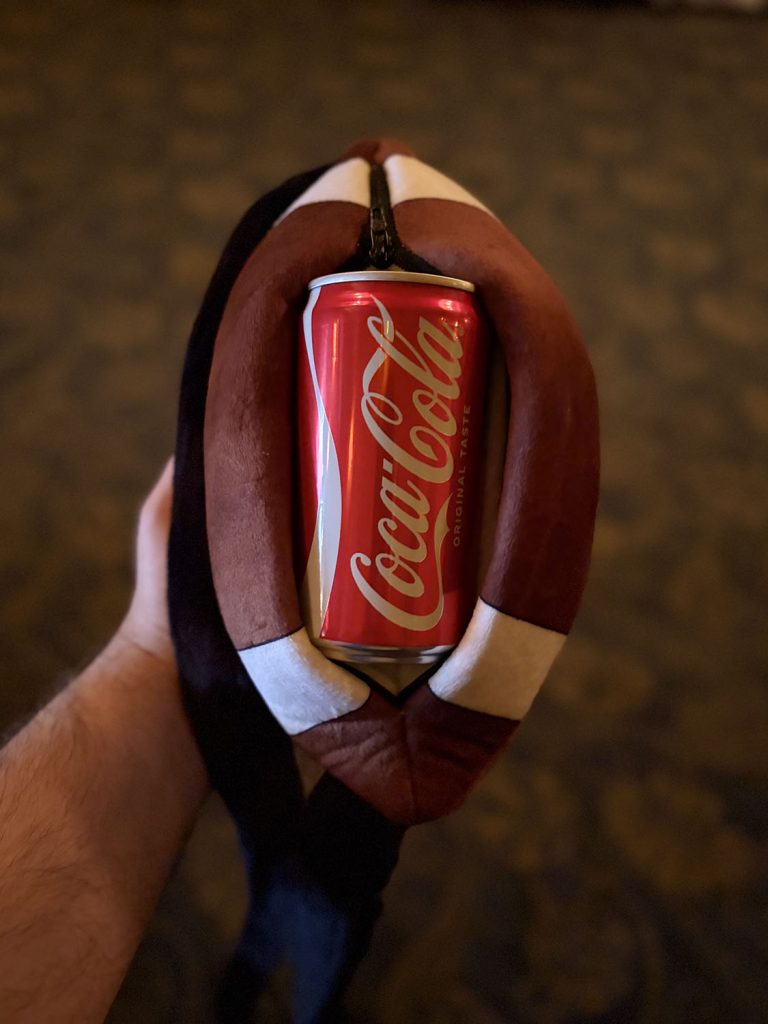 Person holding a flattened football with a can of Coke