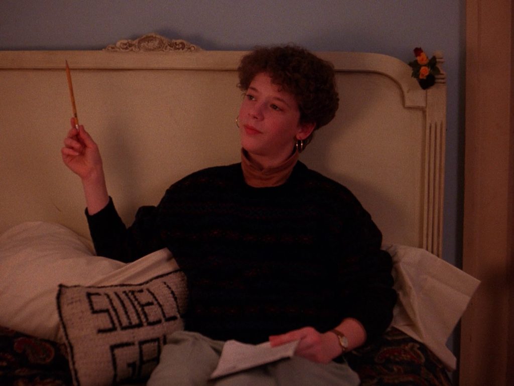 Harriet Hayward sitting on a bed with a "Swell Gal" pillow