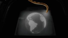Picture of Earth on a screen with a golden machine hanging above it