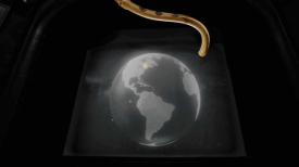 Picture of Earth on a screen with a golden machine hanging above it