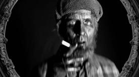Guy dressed as a Woodsman and smoking a cigrette